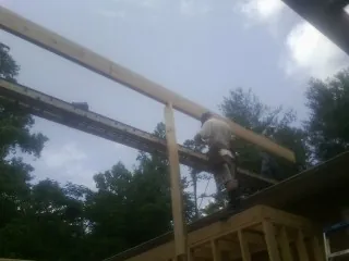Carpenter setting a ridge beam over a new addition frame — Ice Dam Removal by Roofing Brothers in Galveston