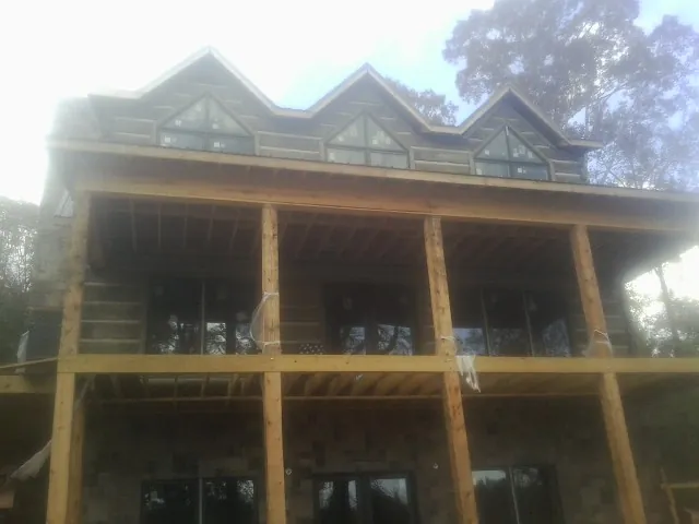 Dormers and porch framing on a large log home under construction — Roof Coating work by our crew in Galveston