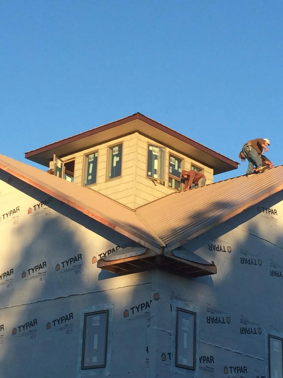 Roofers working around a rooftop cupola on a new metal roof at sunset — Roof Waterproofing in Galveston by Roofing Brothers